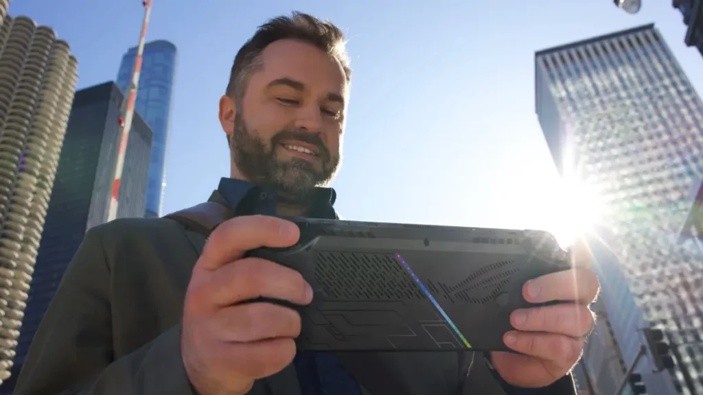 Person holding ASUS ROG Ally X handheld console outdoors demonstrating portable gaming capabilities