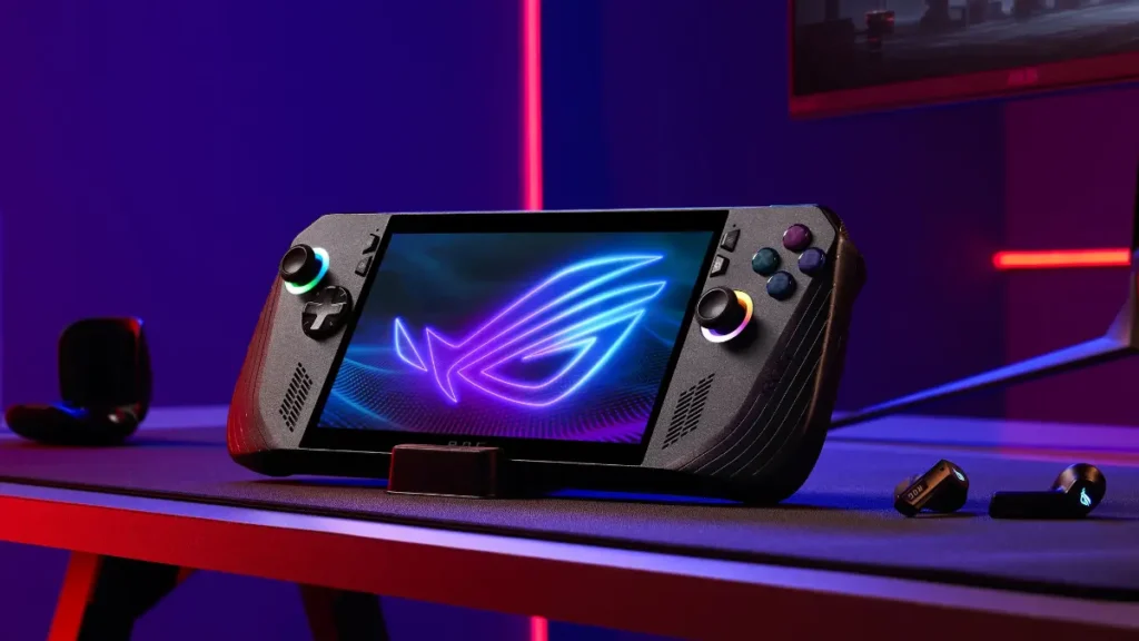 ASUS ROG Ally X handheld gaming console on gaming desk with RGB lighting and ROG logo display